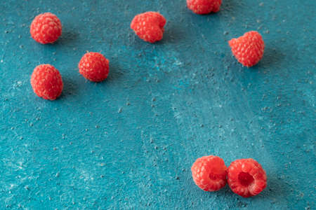 fresh ripe raspberries on a blue textured background with copy space