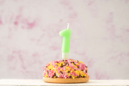 a small coloruful cupcake with number one shaped candle for birthday celebrationの写真素材