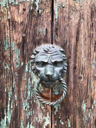 closeup lion head shaped doorknob of an old wooden doorの写真素材