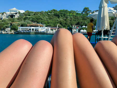 bronze legs of women sunbathing on the beach in summerの写真素材