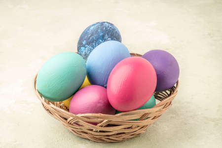 closeup colorful easter eggs in a basket on a soft green background