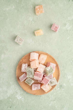 colorful Turkish delights on the plate on a green table with copy space