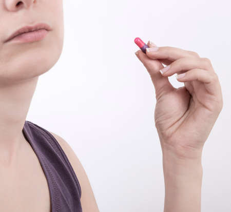 a young woman taking pill over white background with copy space