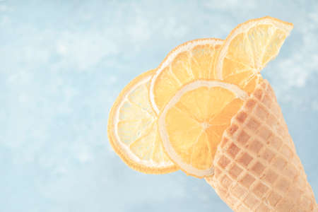 dried lemon slices in an ice cream cones over blue background with copy space