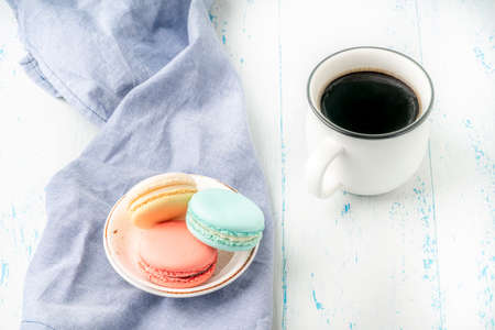 colorful macaroons and cup of coffee on wooden table with copy space