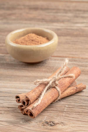 closeup dried cinnamon sticks and powder on the wooden table with copy space