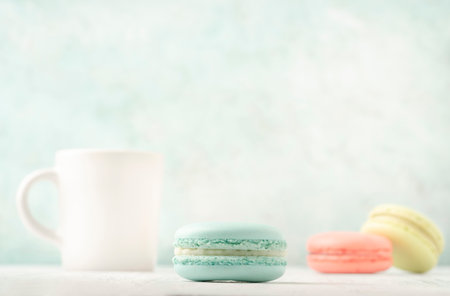 colorful macaroons and cup of coffee on table over green background with copy spaceの写真素材