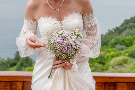 closeup hands of a bride holding wedding flower bouquet, outdoorの写真素材
