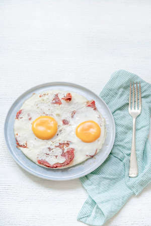 closeup fried eggs with bacon on a wooden table for breakfastの写真素材