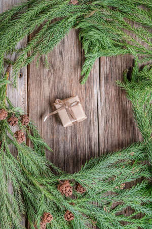 a small gift box on a wooden background decorated branch of pine tree for christmasの写真素材