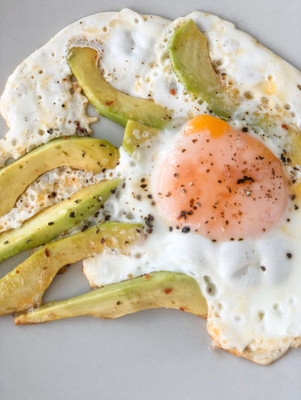 fried egg with avocado slices on plate for a healthy breakfastの写真素材