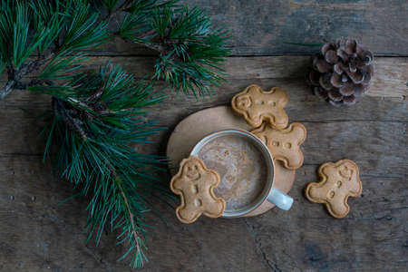 Christmas cookies, Cappuccino or Latte coffee and gingerbread man cookies on wooden table decorated...