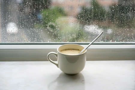 soup, homemade soup in a bowl on windowsill in a rainy day. rain drops on windowpane. mug or cup with selective focus by window while rainingの写真素材