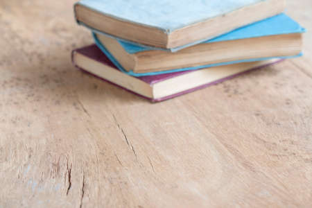 books, heap of hardcover books on the wooden table with selective focus. blurred books as an education background with copy space. education or literature concept photoの写真素材