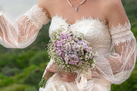 wedding bouquet, closeup hand of bride holding flower bouquet outdoor. body part of woman wearing...