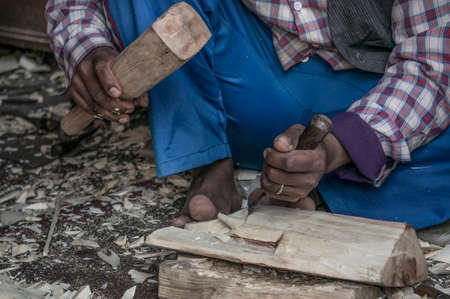 carpenter, closeup male hands of a local carpenter carving wooden masks or objects in Asia or Africa