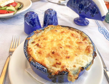 greek food, delicious traditional moussaka with bÃ©chamel sauce cooked in a casserole on table in Greece. typical greek moussaka made from aubergine. local food concept.の写真素材