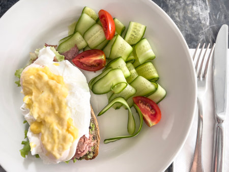 egg, top view delicious poached egg Benedict on toasted bread spread avocado served with fresh salad on plate for breakfast or lunch. healthy diet food concept on plate on marble table or backgroundの写真素材