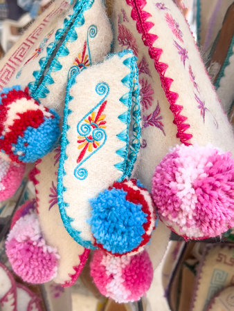 slippers, hanged colorful traditional greek wool handmade slippers or home shoes in a souvenir shop in Greece. traditional local wool socks or shoes as a background. souvenir shop in greece.の写真素材