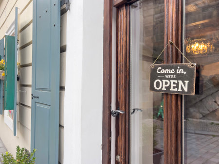 open sign, vintage come in we are open entrance sign hanged on a window door of a small shop or store. entrance of a cafe or shop with sign. small business concept backgroundの写真素材