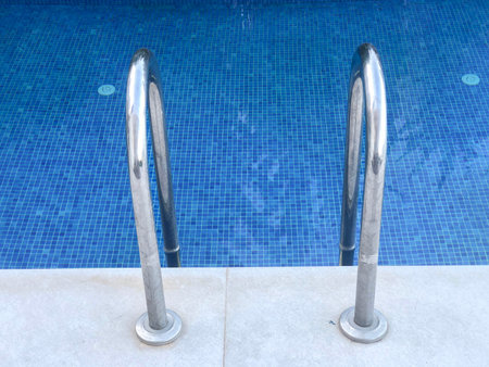 pool, side view chrome ladder of beautiful and clean blue swimming pool with copy space. resort or summer holiday concept background or surface. summer sports or activity surface with copy spaceの写真素材