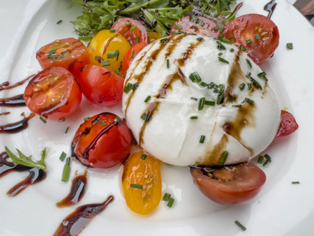 food, Traditional Italian salad with Burrata cheese and cherry tomatoes. caprese salad with delicious burrata cheese cherry tomatoes pesto and balsamic sauces. Italian cuisine background or surface.の写真素材