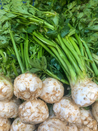 raw vegetables, heap of fresh celery root vegetables with green leaves on the market stalk. raw food...