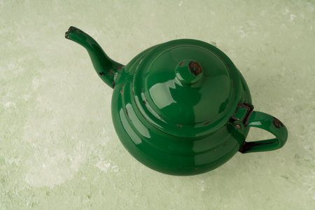 top view retro enamel teapot isolated on green background or surface with copy space. vintage objects. green enamel teapot on table with copy space. retro conceptの写真素材