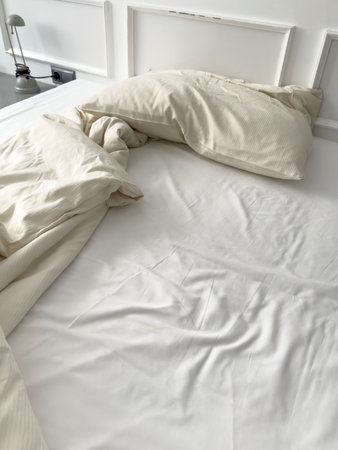 Messy bed. used pillow, blanket on bed unmade. pillow on unmade bed with wrinkle messy blanket in...