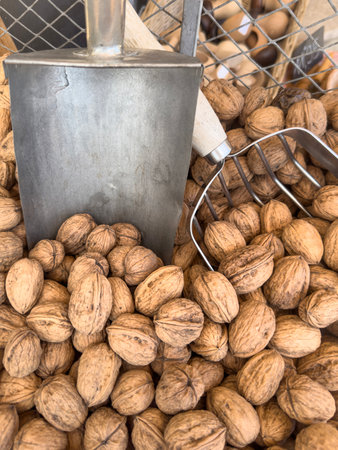 dry fruit, Organic whole walnuts in brown shell displayed in bulk at market with rustic metal scoop...
