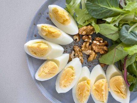food, Nutritious breakfast plate featuring sliced boiled eggs, crunchy walnuts, and fresh mixed green salad. healthy diet, clean eating, and balanced lifestyle. closeup Ketogenic breakfast plateの写真素材