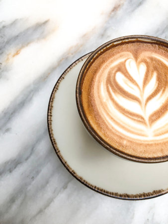 coffee, top view Freshly brewed cappuccino with latte art in ceramic cup on marble surface or table....