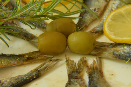Anchovy with lemon, rosemary and olives on plateの写真素材