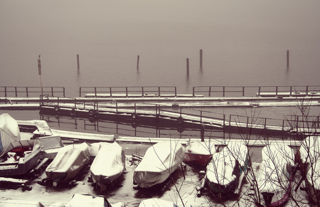Several boats covered with snow near the shore covered. In the background begins to freeze, covered with thin ice river, mistical landscapeの写真素材