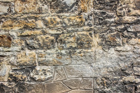 Ancient brick wall with different size of stones, close up photo. Texture or background.