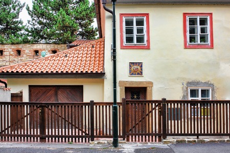 Brown wood fence in front af a house with orange shingles roof.の写真素材