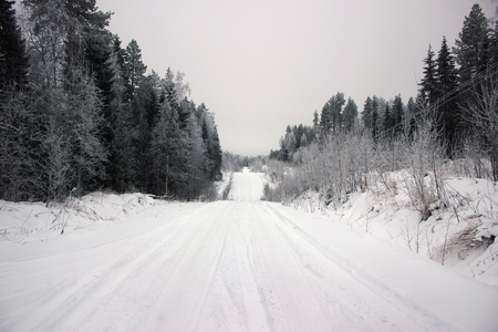 Empty road with huge snow banks on sides on cloudy winter dayの写真素材