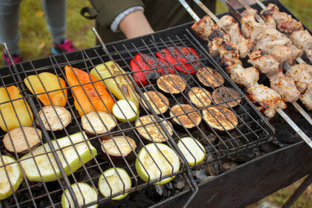 Grilled vegetable and meat skewers in a herb marinade on a grill, cooked in nature, top view.の写真素材