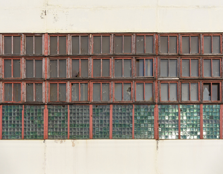 Large long windows in a large old abandoned industrial factory building, closeupの写真素材