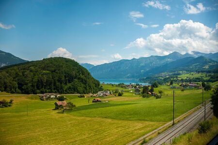 Beautiful swiss landscape. View from the train to a small village near the lake, mountains. Picturesque and gorgeous scene. Switzerlandの写真素材