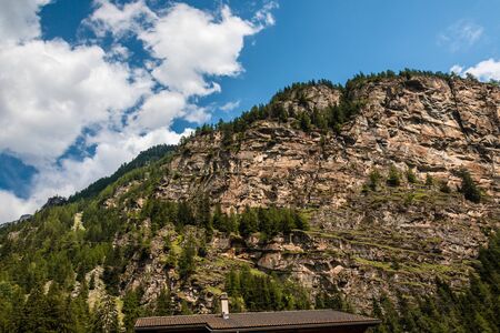 Sheer cliff with trees on a beautiful sunny day with blue sky and cloudsの写真素材