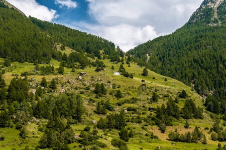 A small village with a church in the Swiss Alps. View of the green slope in the mountains. Idyllic outdoor scene in Switzerland, Europeの写真素材