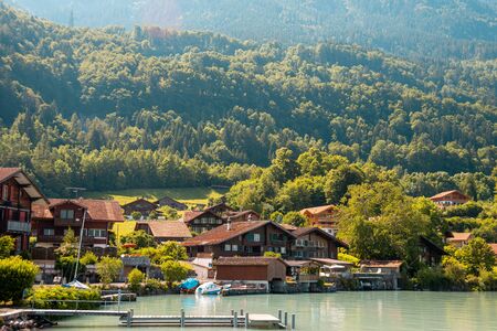 View of Brienz lake with clear turquoise water. Traditional wooden houses on the shore of Brienz lake in the village of Iseltwald, Switzerlandの写真素材