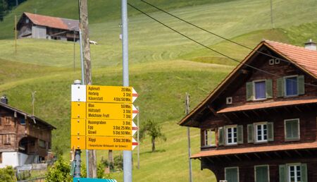 Yellow directional road signs. Wooden house in the backgroundの写真素材