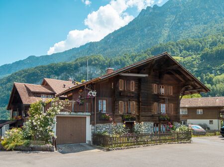 Beautiful traditional wooden house in the alpine village, Switzerland. House decorated with flowers, near flowerbedの写真素材