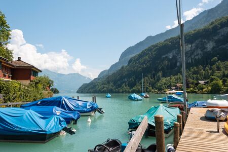 Wooden pier with boats. Beautiful lake with turquoise water and rocky shores with forestsの写真素材