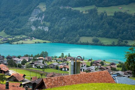 View of the roofs of traditional swiss houses swiss village Lungern. Stunning turquoise Lake Lungerersee with clear water, canton of Obwalden, Switzerland. Incredibly bewitching and calm place.の写真素材