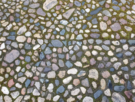 Cobblestone street with grass between the stones, multi-colored cobblestones, rubble masonry, texture or backgroundの写真素材