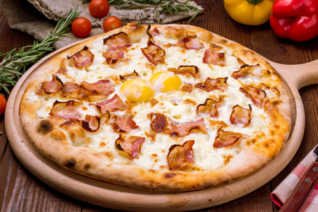 Carbonara pizza with bacon and egg on wooden tableの写真素材