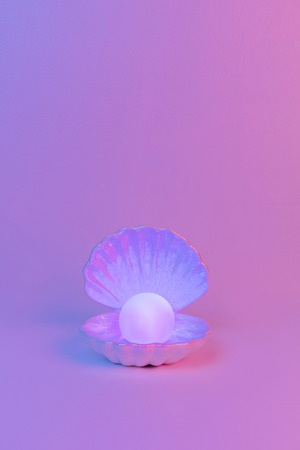 Pastel neon blue and pink light paint on seashell and pearlの写真素材